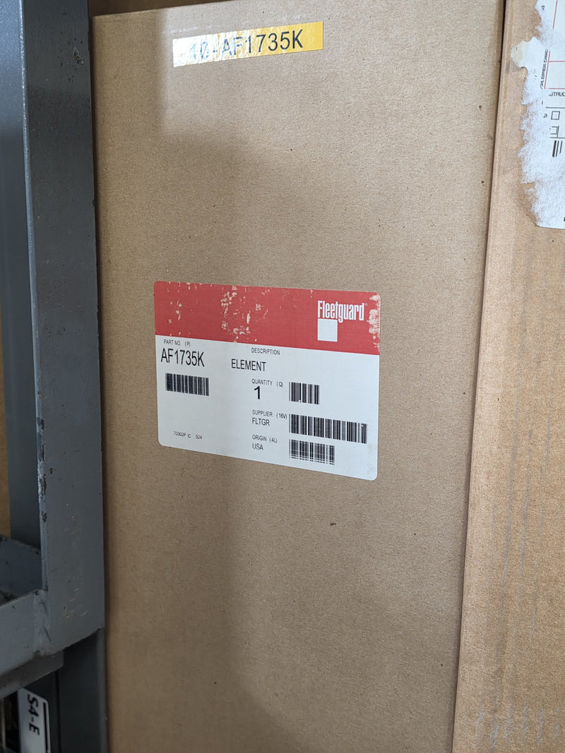 Genuine Fleetguard AF1735K air filter element in a sealed carton with a yellow shelf tag above it, origin USA, photographed on rack S4-E in Prince George BC